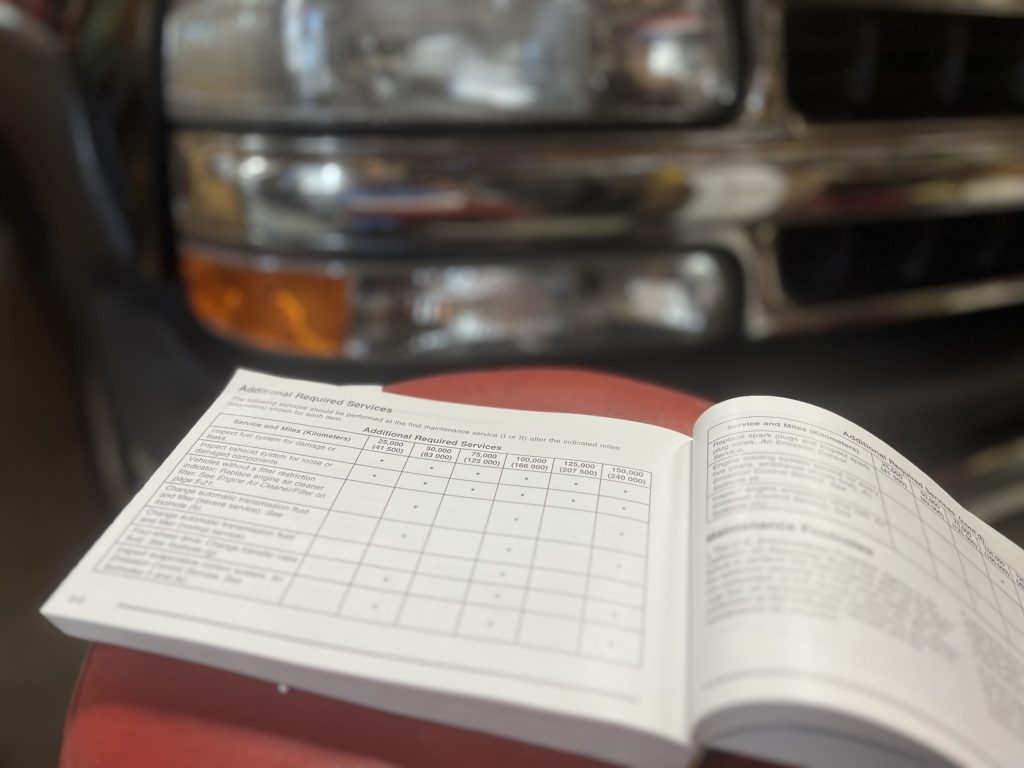Photo of a car owner's manual on a shop stool in front of the vehicle showing the ongoing maintenance log that's similar to the one you need when launching a new software product.