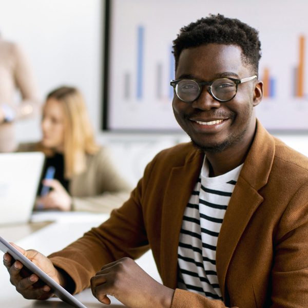 Handsome young African American business man working with digital tablet in front of his coworkers at boardroom